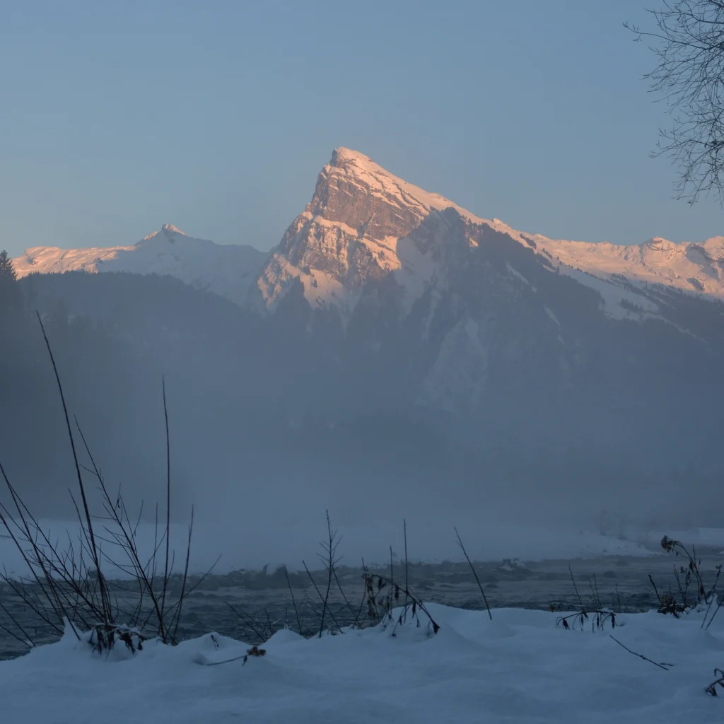 Le Criou éclairé par un soleil couchant avec une brume hivernale remontante du Giffre