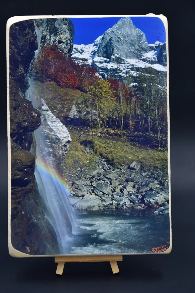 Tableau d'une photo collée sur du bois La photo est celle d'une cascade prise au cirque du Fer A Cheval, avec un arc en ciel qui se forme dans la cascade et au loin les sommets enneigés